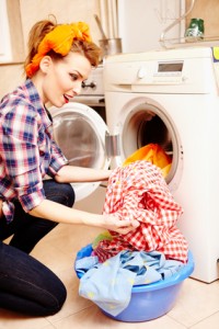 Housewife putting the laundry into the washing machine